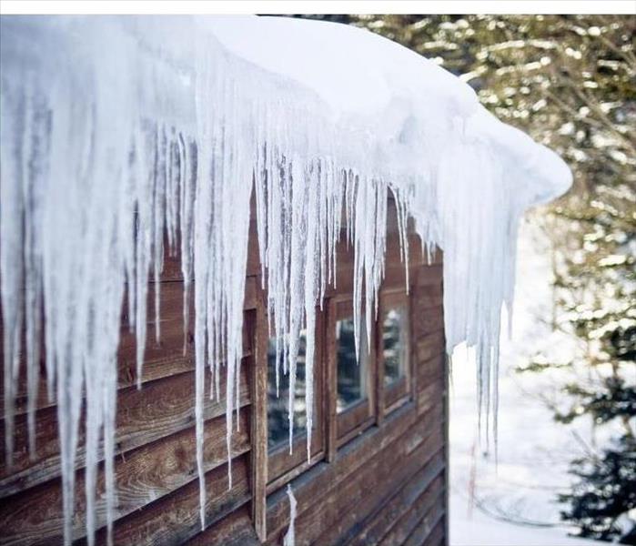 Icicles hanging from a snow covered roof top. 